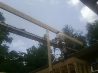 Carpenter setting a ridge beam over a new addition frame — Ice Dam Removal by Roofing Brothers in Pacific Grove