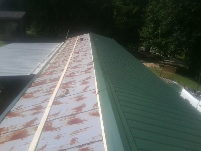 Old rusted panels beside newly installed green metal roofing — Wind Damage Roof Repair by Roofing Brothers in Pacific Grove