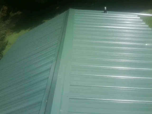 New green metal panels meeting at the ridge of a roof — Flat Roof Repair work by our crew in Pacific Grove