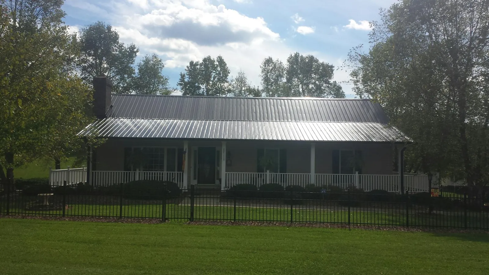 Gray metal roof on a brick ranch with a full width front porch — Gutter Guard Installation work by our crew in Pacific Grove
