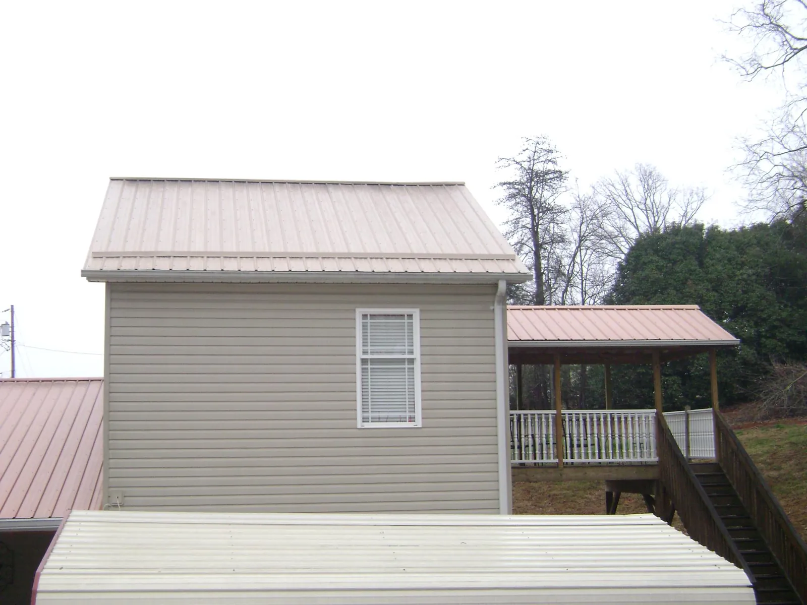 Tan metal roofs on a two story addition and attached porch, from a Roof Replacement job in Pacific Grove