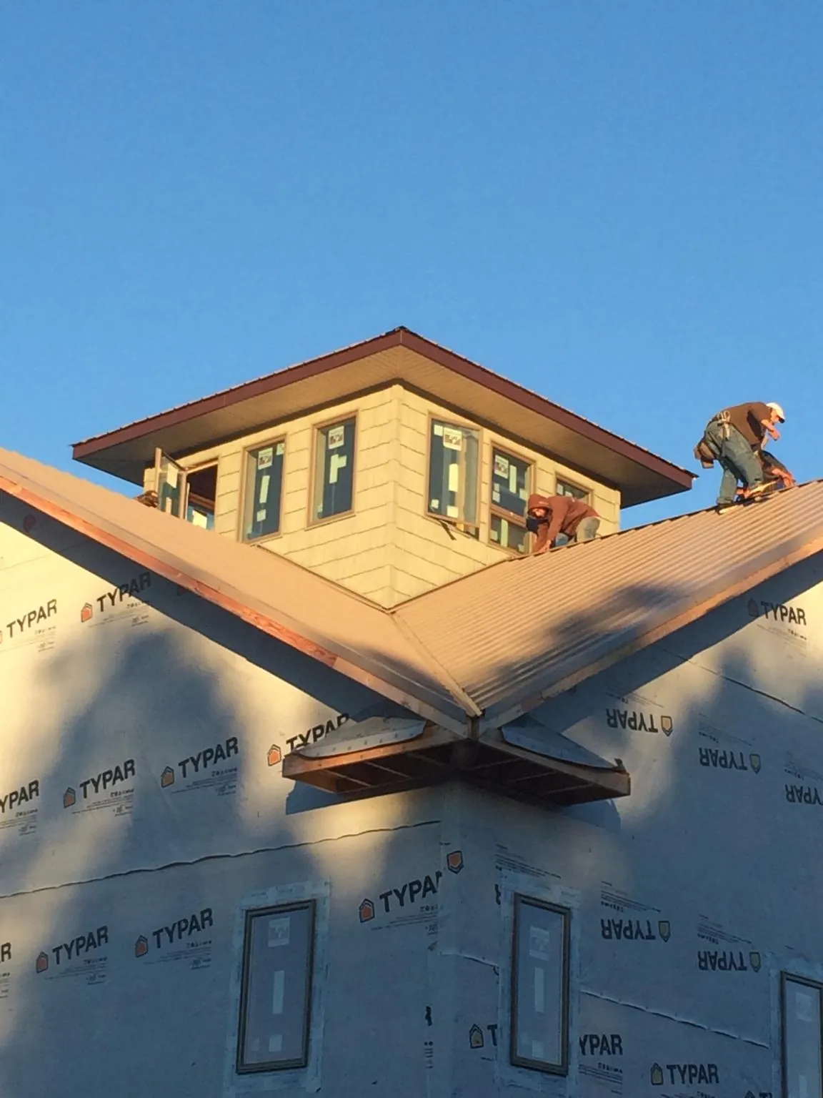 Roofers working around a rooftop cupola on a new metal roof at sunset — Roof Waterproofing in Pacific Grove by Roofing Brothers